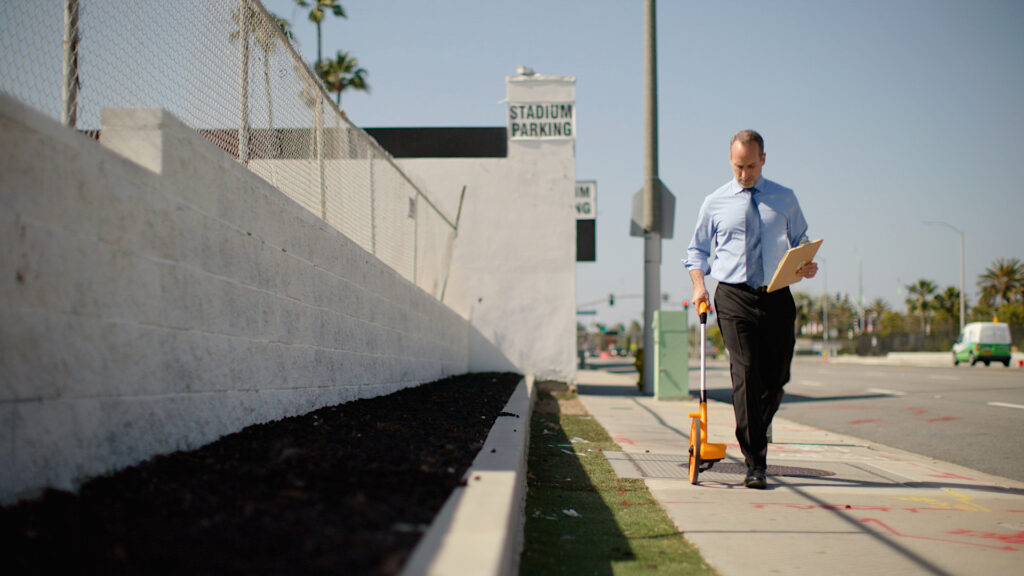Adam measures the sidewalk.
