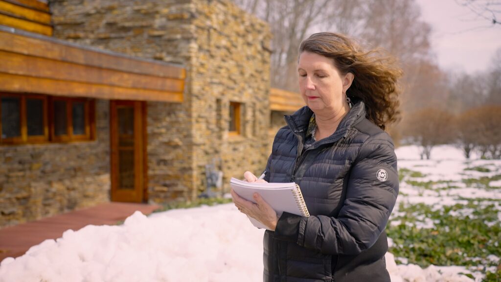 Emily takes notes on the exterior of a home.